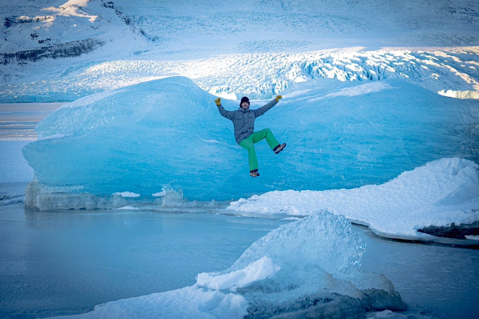 Viajero saltando frente a un glaciar