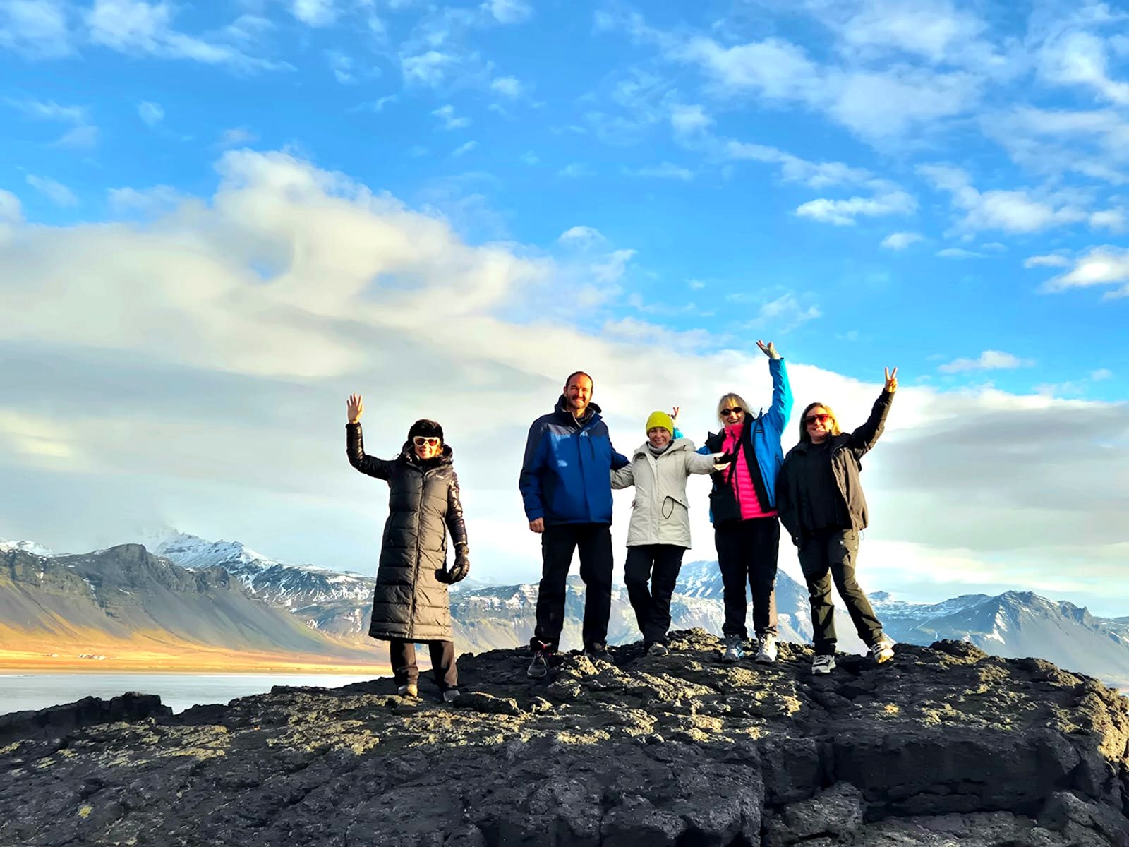 Viajeros celebrando sobre rocas frente a montañas