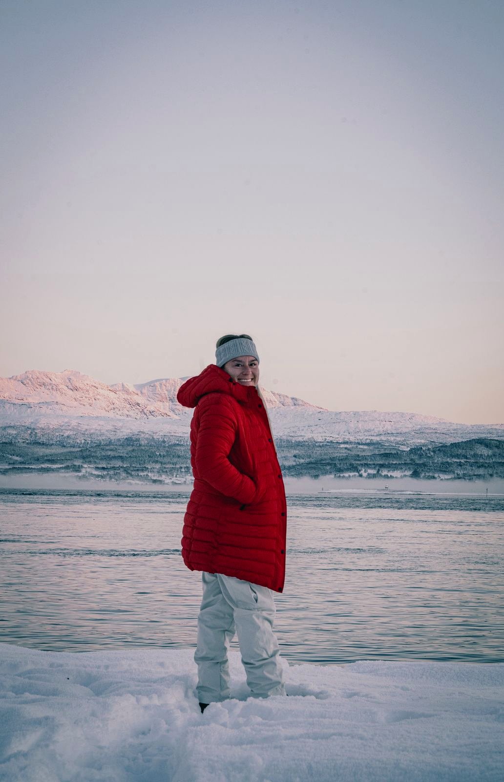 Viajera con plumífero rojo junto al agua