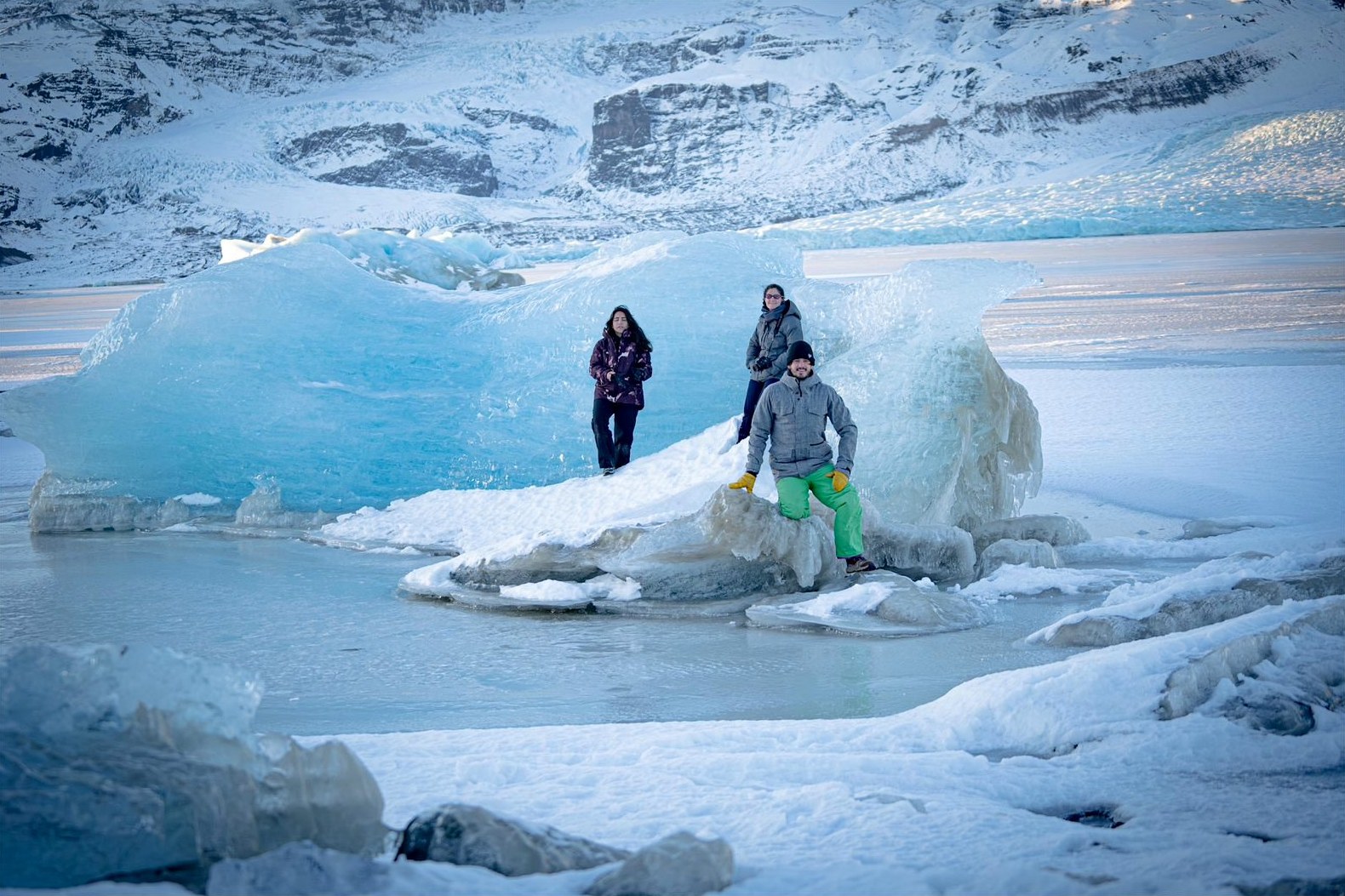 Tres viajeros sobre hielo azul frente al glaciar