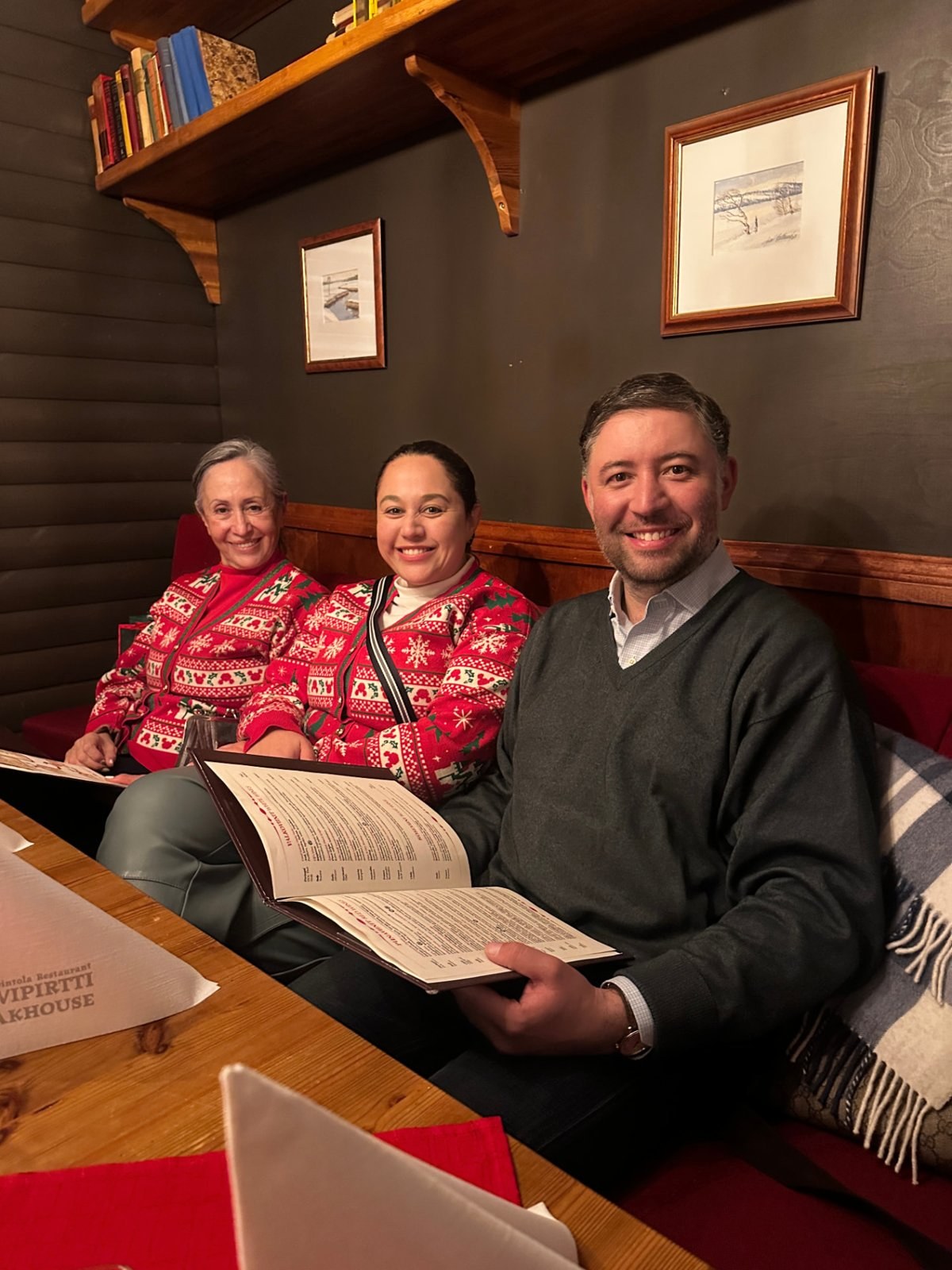 Tres viajeros sonriendo alrededor de una mesa
