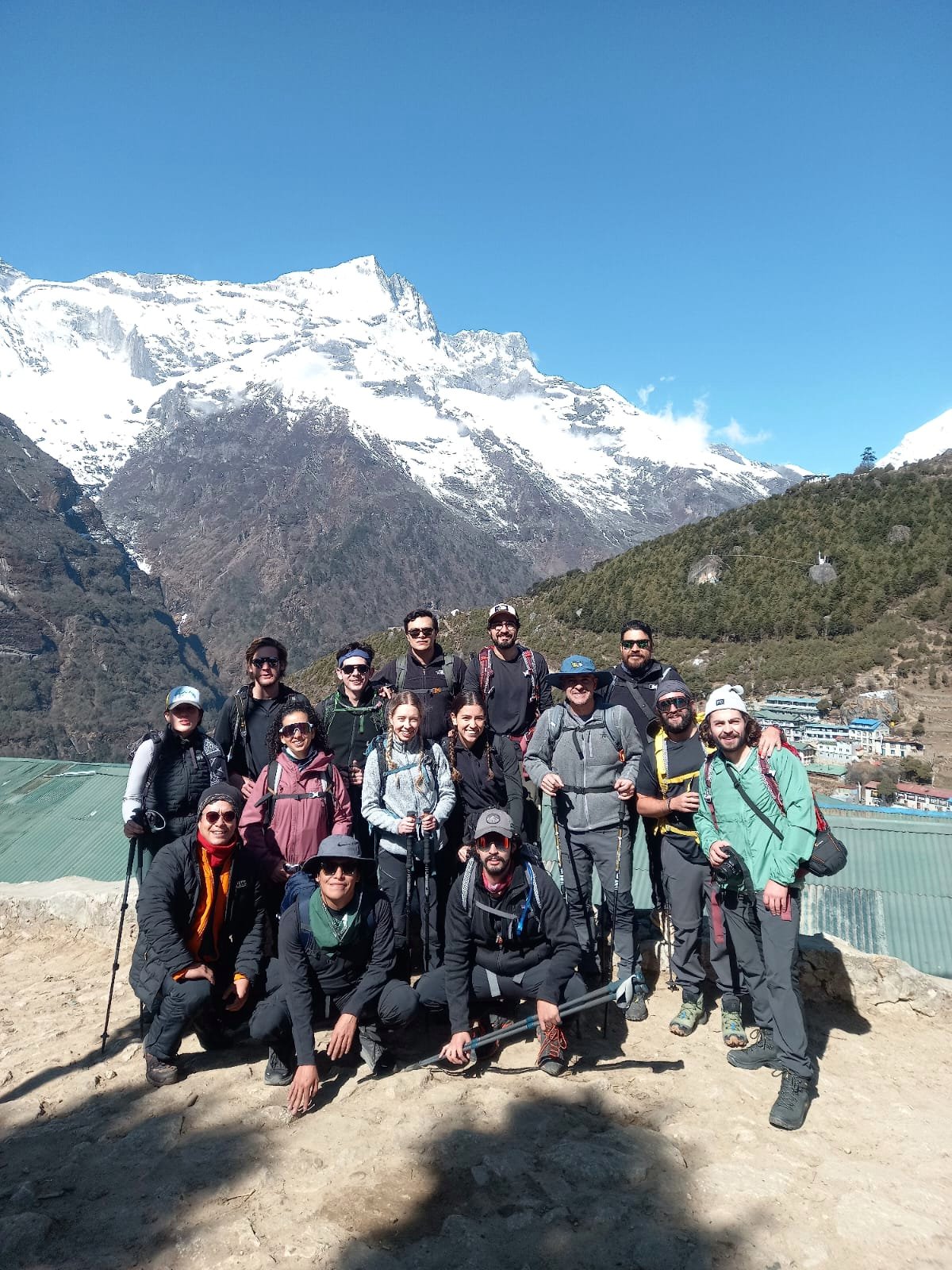 Grupo de viajeros junto a un lago y montañas nevadas