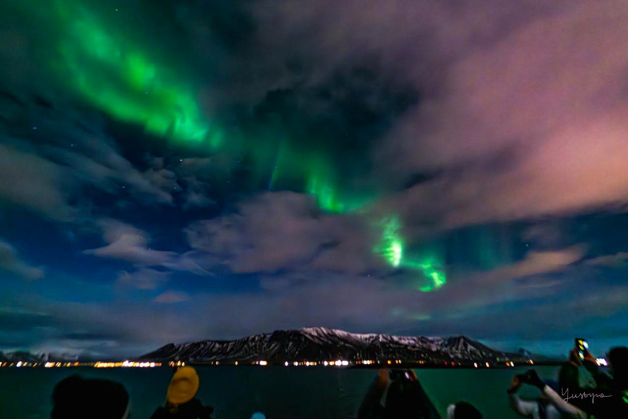 Aurora boreal sobre el agua y las montañas