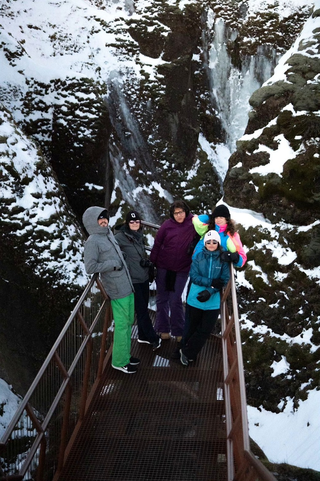 Grupo de viajeros en un puente entre cascadas nevadas