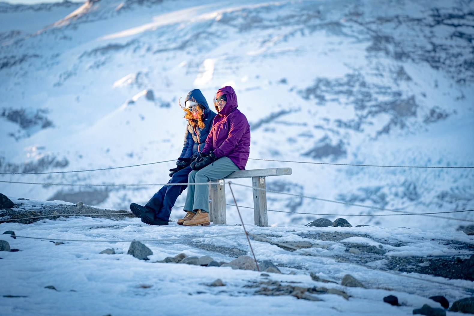 Dos viajeras sentadas frente a montañas nevadas