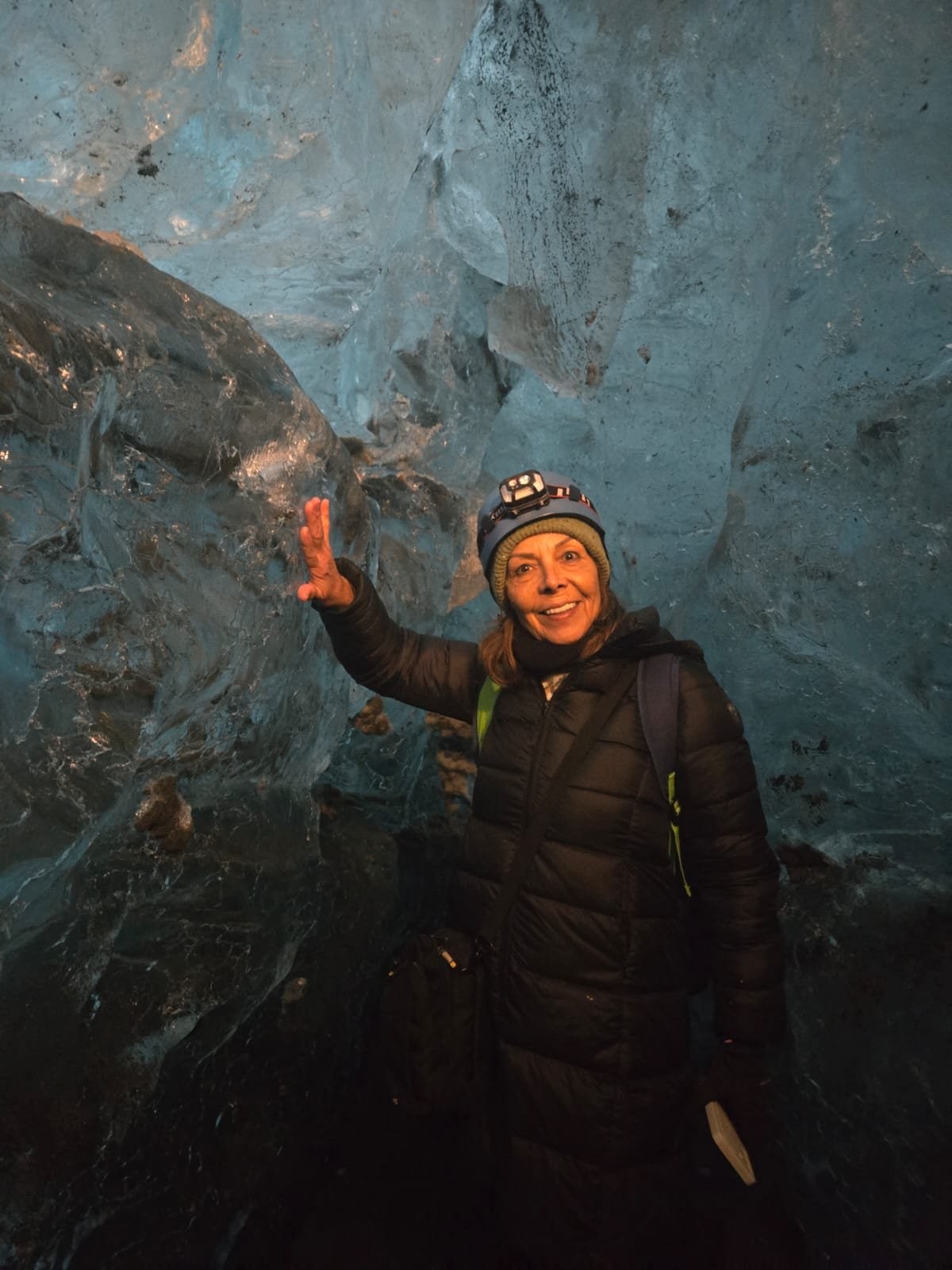 Viajera con casco junto a una pared de hielo