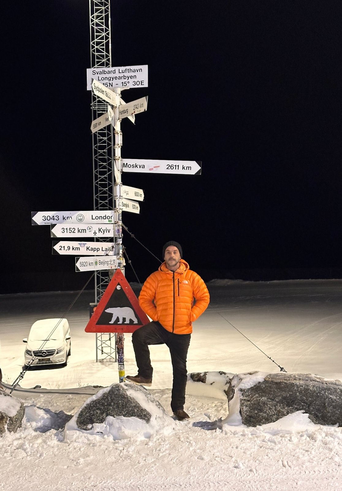 Viajero con chaqueta naranja junto a señales en la nieve
