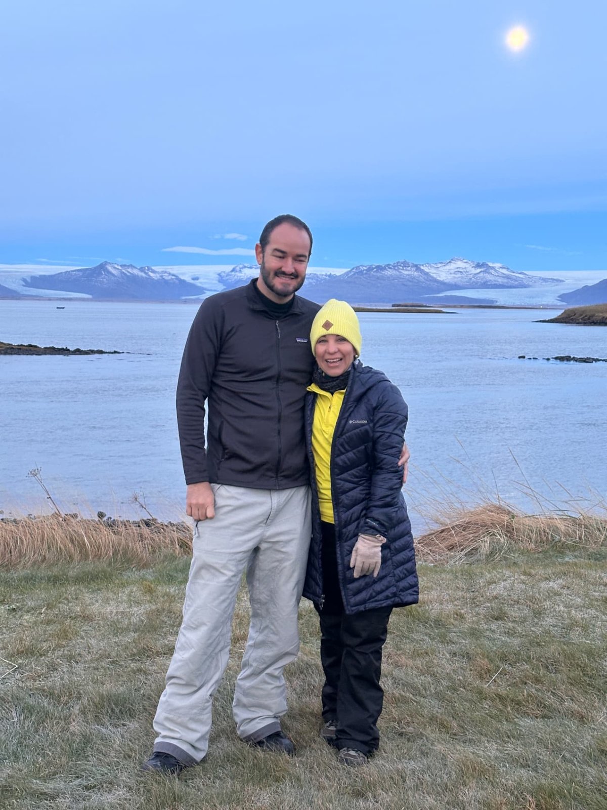 Dos viajeros junto al lago y montañas