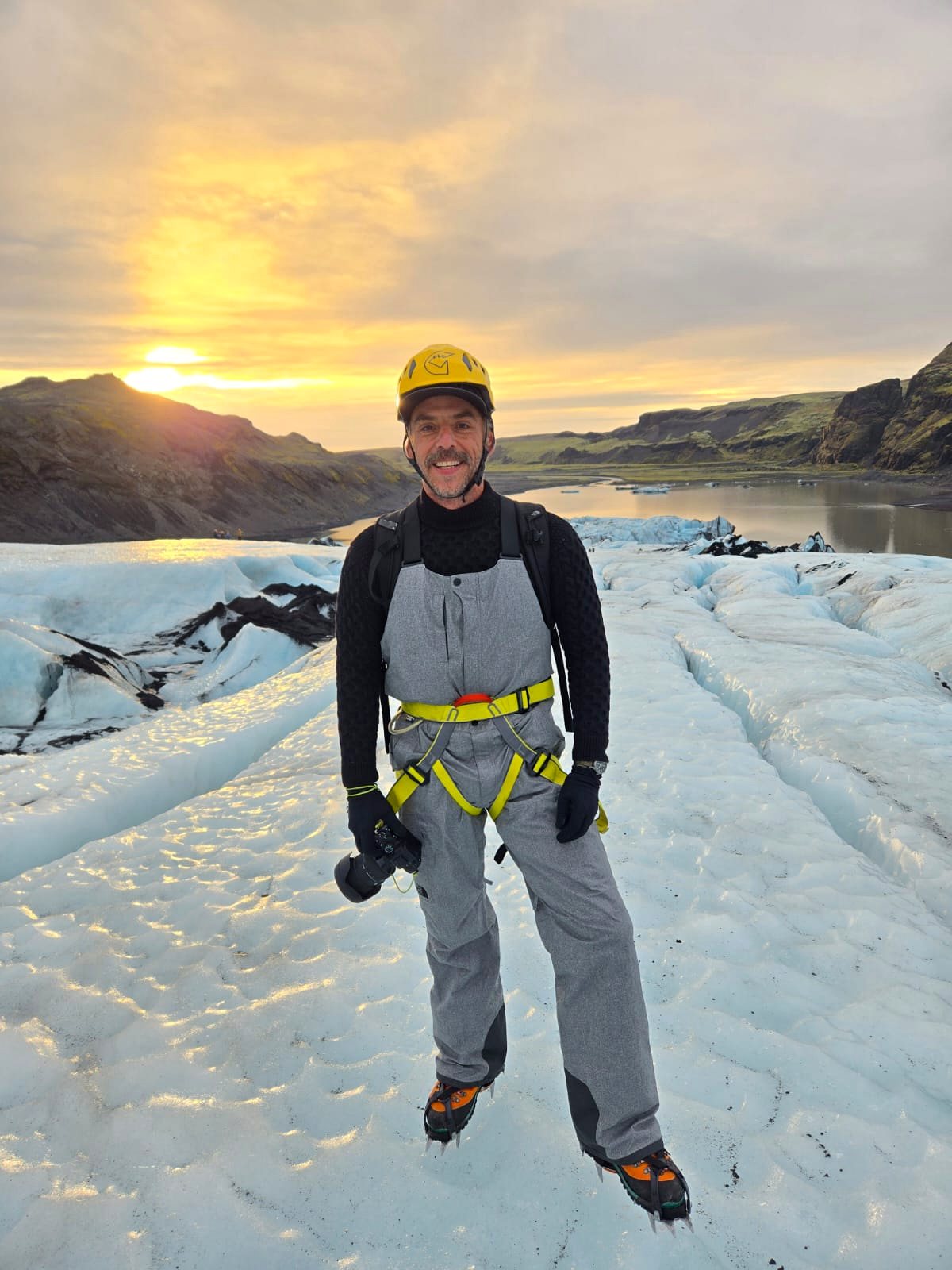 Viajero con casco sobre un glaciar al atardecer