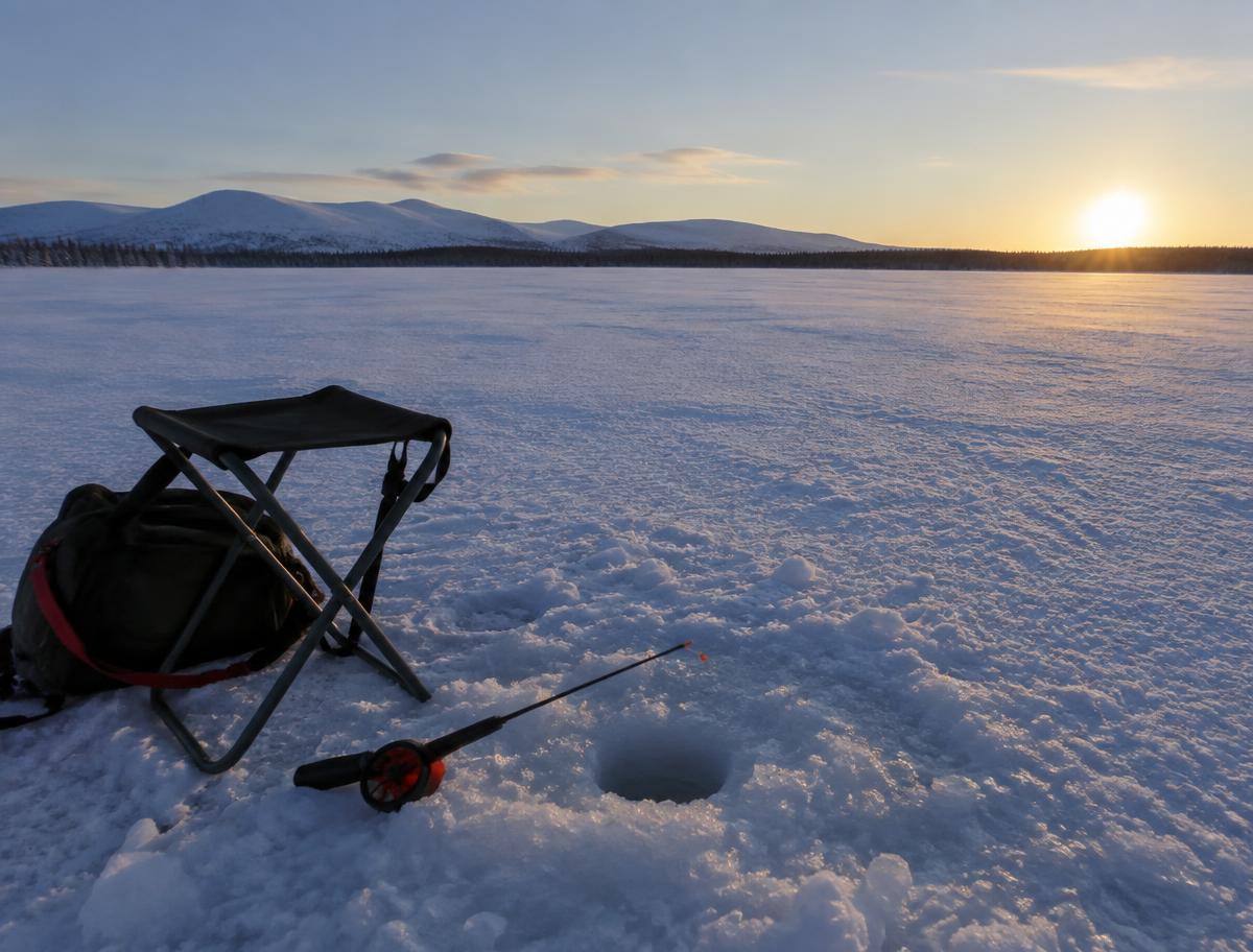 Pesca en hielo sobre un lago congelado en Laponia
